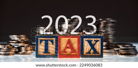 TAX word with coin, pay taxes concept - wooden blocks on coin stacks on 2023 year