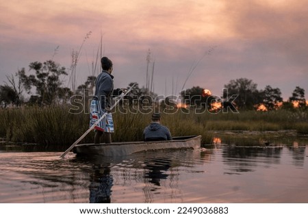 Okavango Delta savannah mirrored in water, as mokoro poles through