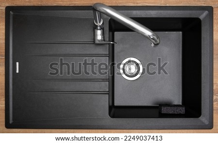 New clean granite kitchen sink black, strainer, holder for kitchen sponge. After. Drops water. House cleaning service. Top view Royalty-Free Stock Photo #2249037413