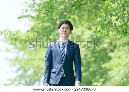 Asian businessman walking in the fresh greens Royalty-Free Stock Photo #2249038073