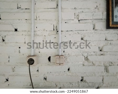 White brick wall with electrical installation. Plug in,  socket,  wire