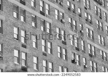 A black and white photo of an old residential building with brick facade and windows, New York City, USA.