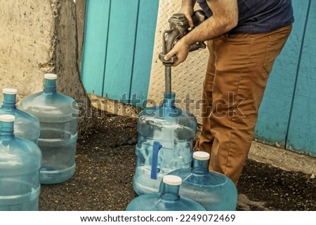 Young man filling five gallon jugs for use in dry cabin - with no running water- in Alaska USA
