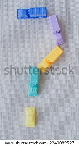 Horizontal framing of the interrogation sign ?. This photography is a part of a conceptual image serial illustrating a sign or a letter using toy pastel colored plastic cars and trucks.