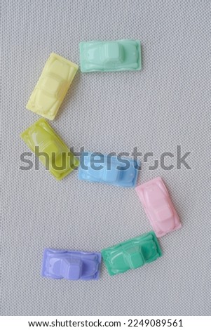 Horizontal framing of the letter S. This photography is a part of a conceptual image serial illustrating a sign or a letter using toy pastel colored plastic cars and trucks.