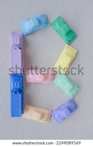 Horizontal framing of the letter B. This photography is a part of a conceptual image serial illustrating a sign or a letter using toy pastel colored plastic cars and trucks.