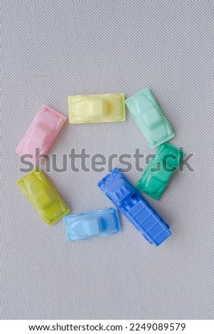 Horizontal framing of the letter Q. This photography is a part of a conceptual image serial illustrating a sign or a letter using toy pastel colored plastic cars and trucks.