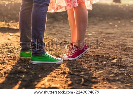 A woman stands on her tiptoes to kiss a man. A man and a woman in the same sneakers of different colors. Valentine's Day. Vertical photo Royalty-Free Stock Photo #2249094879