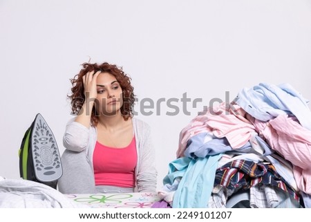 The woman can't believe she has so many men's shirts to iron this time.