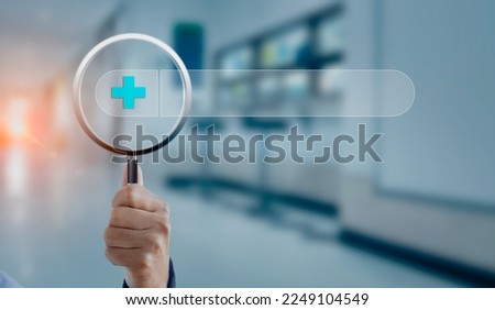 Magnifying glass in hand with healthcare and medical icons on hospital room background.
