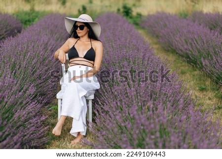 fashion outdoor photo of beautiful woman with dark hair posing in bloomig lavender field on sunset. High quality photo