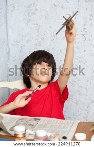 boy in a red shirt with a wooden plane and brush
