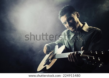 Guitarist playing acoustic guitar. Unplugged performance in the dark.