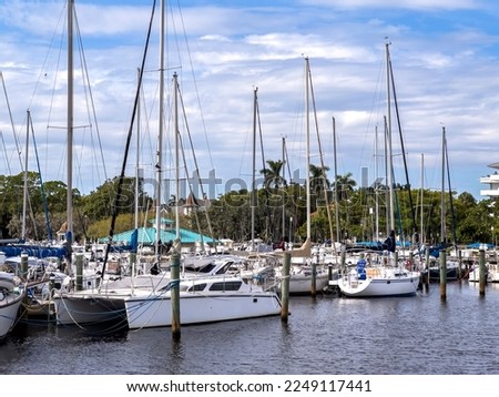 Catamaran (left foreground) and other yachts moored in a tidal river marina at the edge of a city near the Gulf of Mexico on an autumn afternoon in southwest Florida