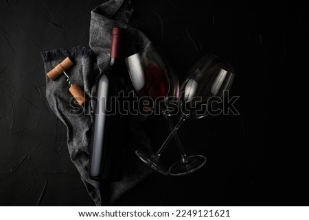 Red wine bottle with glasses on dark background 