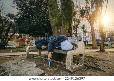 Homeless man or alcoholic sleeping on bench. Poor man on city street. Royalty-Free Stock Photo #2249126397
