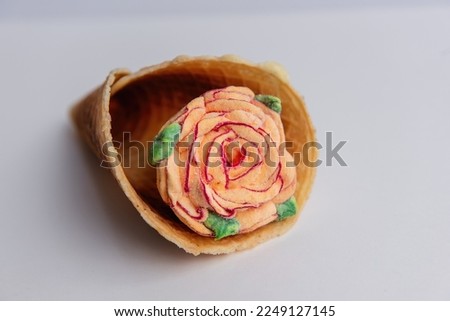 Waffle cone with sweet pastel orange marshmallow roses on a light isolated background. Mock up, copy space. Small business, pastry hobby. Natural dessert without sugar