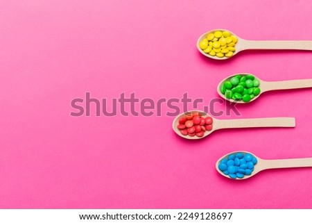 delicious colorful sweet candies on spoon on colored background . Confectionery decor top view with copy space.