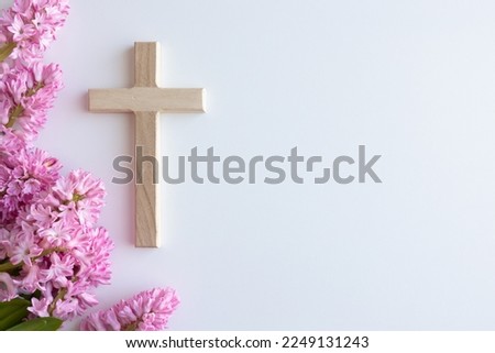 Small wood Christian cross and border of pink hyacinth flowers on a white background with copy space