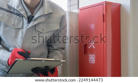 A worker who inspects a fire extinguisher. The word "fire extinguisher" in Japanese.