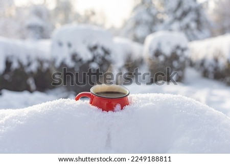 Red cup with coffee on snow in the park christmas background