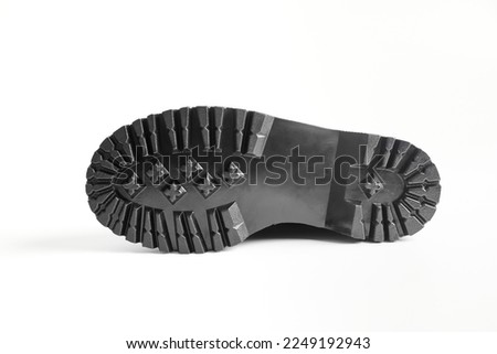 Lug sole of black combat boots on high heel platform lying on isolated white background. Bottom of military stylish notched soles high heel platform combat boots for woman legs, new footwear trends