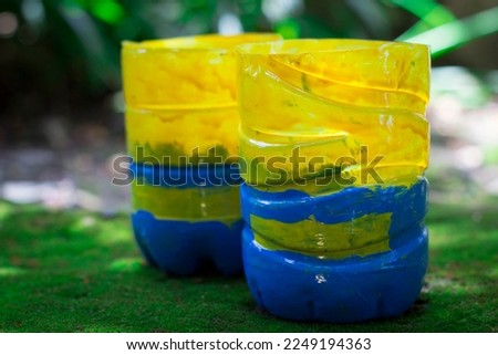 Handycraft of plants pot used by mineral plastic bottle, yellow and blue combination, Minion cartoon concept, put on the mossy ground