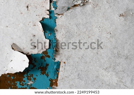 Torn old faded paper wallpaper on the wall. Ragged scraps of white paper on a blue background. Vintage texture for background and design. Closeup view with copy space for text. High resolution.