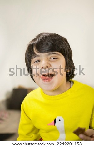 Closeup of a funny child boy eating the whole bar of chocolate and licking his face - Childhood. Stock image of a happy little boy wearing casual clothes and eating chocolate , candy and licking