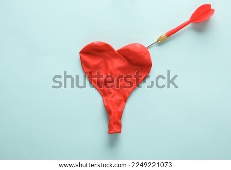 Dart and inflates red heart shaped balloon on blue background. Love concept Royalty-Free Stock Photo #2249221073