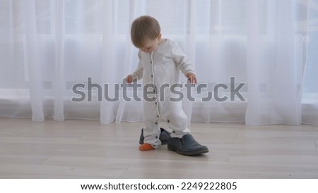 Little baby trying to wear daddy's big shoes Royalty-Free Stock Photo #2249222805