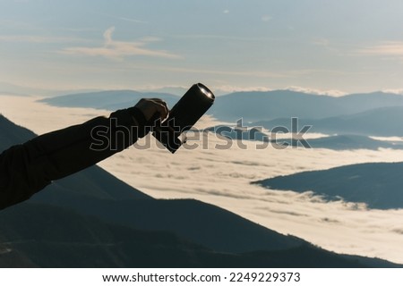 Male hand holding dslr camera against nature background travel photography.