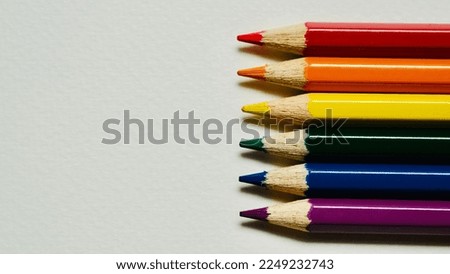 Colored pencils, arranged in the colors of the lgbt flag and with space for letters.
