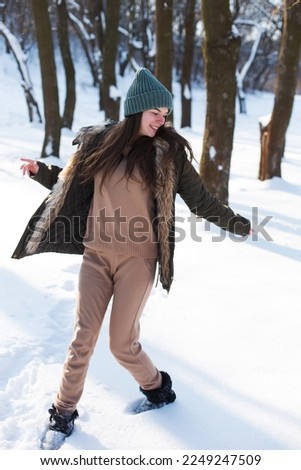A young girl, brunette, in sweater, hat and an green jacket, against the backdrop of the winter landscape. Snow and frost, the concept of Christmas.