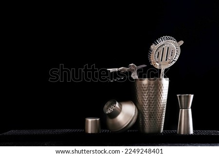 A set of accessories for the work of a bartender. Cocktail set and corkscrew on a black background. Royalty-Free Stock Photo #2249248401