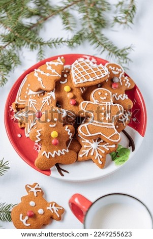 Gingerbread cookies in shape of ginger man placed on red plate. White background. Traditional Christmas dessert decorated. Playful and happy.