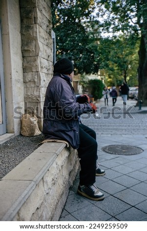 Sad homeless man begs for money at the street. Royalty-Free Stock Photo #2249259509