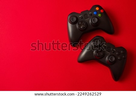 Black video game controller, joystick for game console isolated on red background. Gamer control device close-up