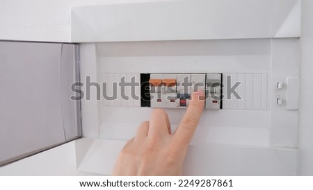 Turning on circuit breaker on control panel after it tripped due to overload Royalty-Free Stock Photo #2249287861