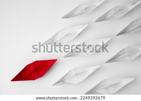 Group of paper boats following red one on white background, flat lay. Leadership concept