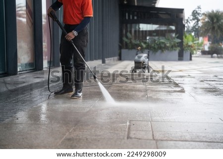 cleaning staff hoses a portable car for washing the concrete floor with high-pressure water jets. Royalty-Free Stock Photo #2249298009