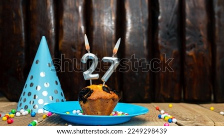 Beautiful anniversary background happy birthday with a cupcake and a burning candle. Happy birthday anniversary on wooden background with decorations with number 27