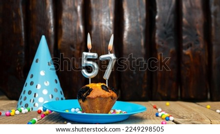 Beautiful anniversary background happy birthday with a cupcake and a burning candle. Happy birthday anniversary on wooden background with decorations with number 57