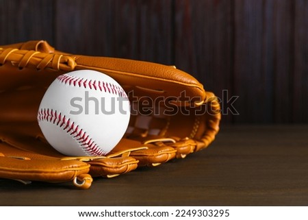 Leather baseball glove with ball on wooden table. Space for text