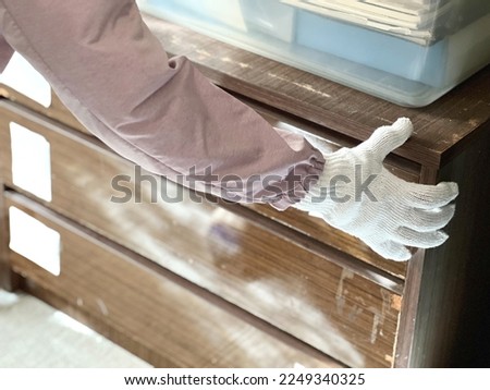 A person wearing gloves with an old chest of drawers Royalty-Free Stock Photo #2249340325