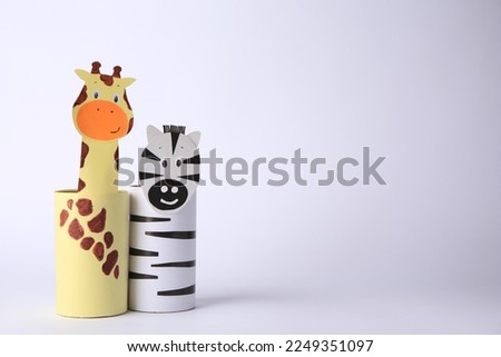 Toy giraffe and zebra made from toilet paper hubs on white background, space for text. Children's handmade ideas
