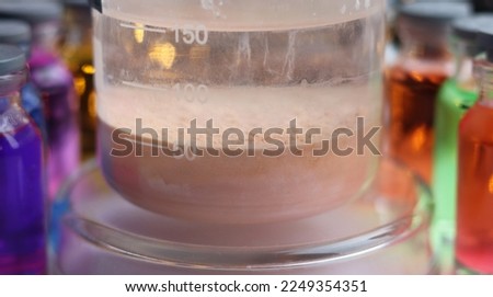 A brown precipitate of manganese sulfide settled at the bottom of the chemical beaker. Royalty-Free Stock Photo #2249354351