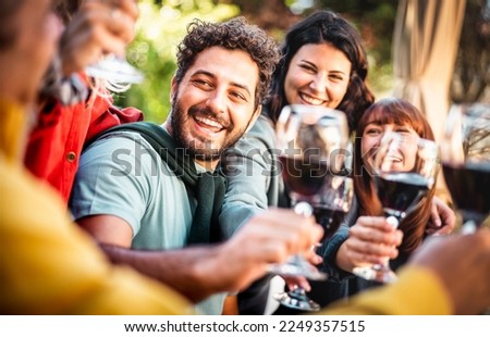 Happy people on genuine mood drinking red wine at pic nic garden party - Millenial friends having fun together at restaurant winery bar out side - Dining life style concept on bright warm filter