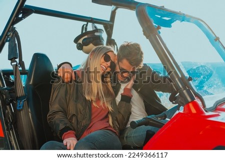 Young happy excited couple enjoying beautiful sunny day while driving a off road buggy car on mountain nature