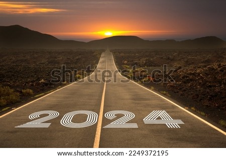 New year 2024 or straight forward concept. Text 2024 written on the road in the middle of asphalt road with at sunset. Concept of planning, goal, challenge, new year resolution, selective focus 
